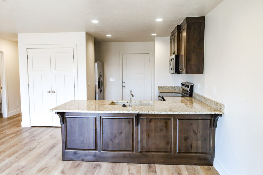 Kitchen with a stone-topped island and dark wood cabinets in a Priority Homes build