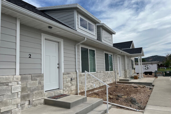 Exterior view of Ray’s Apartments in Nephi, Utah, featuring modern 2-bedroom unit with stone accents, steps leading to the entrance, and landscaped surroundings, emphasizing comfortable small-town living.